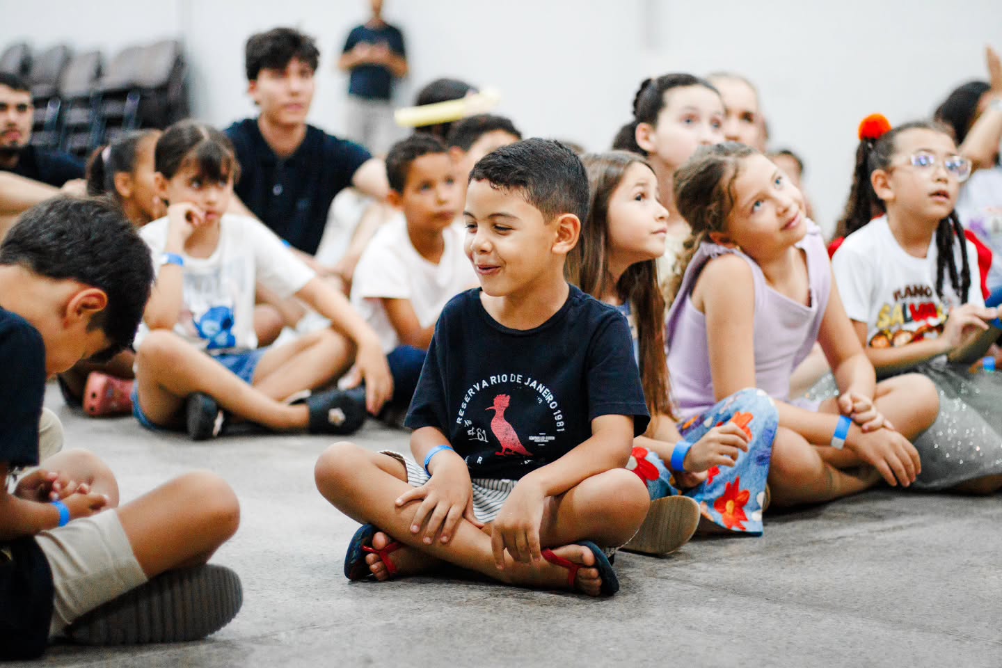 Crianças atentas acompanhando o programa sentadas no chão