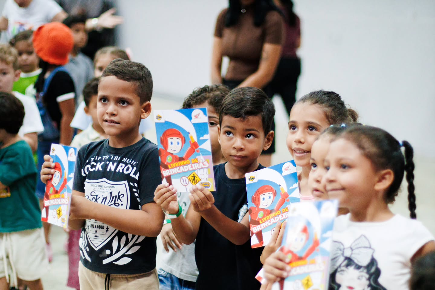 Crianças com os livrinhos de brincadeiras recebidos no evento